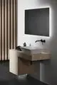 Waschtisch mit quadratischem weißen Waschbecken auf hölzernem Unterschrank, Wandarmatur in Silk Black, beleuchtetem Spiegel im modernen Badezimmer-Design von Ideal Standard.